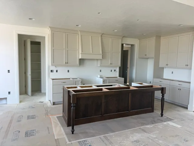Expansive kitchen featuring a large wood-finish island, recessed lighting, white shaker cabinetry, and a walk-in pantry with built-in shelving