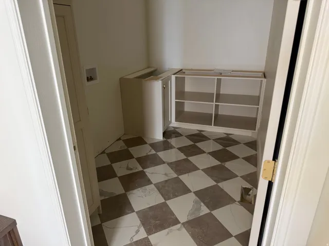Checkered tile flooring, white built-in shelving, and a built-in corner cabinet