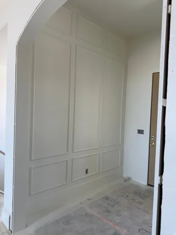 Wall paneling with decorative trim, arched doorway, and a solid core door
