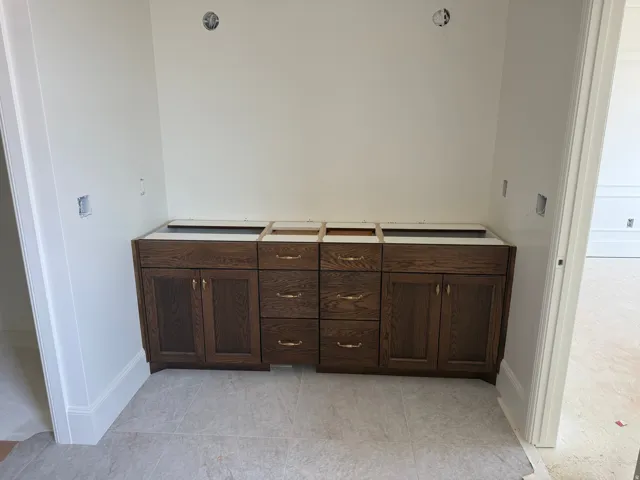 Primary Suite dual vanity base with wood-finish cabinetry, drawer storage, and brass hardware