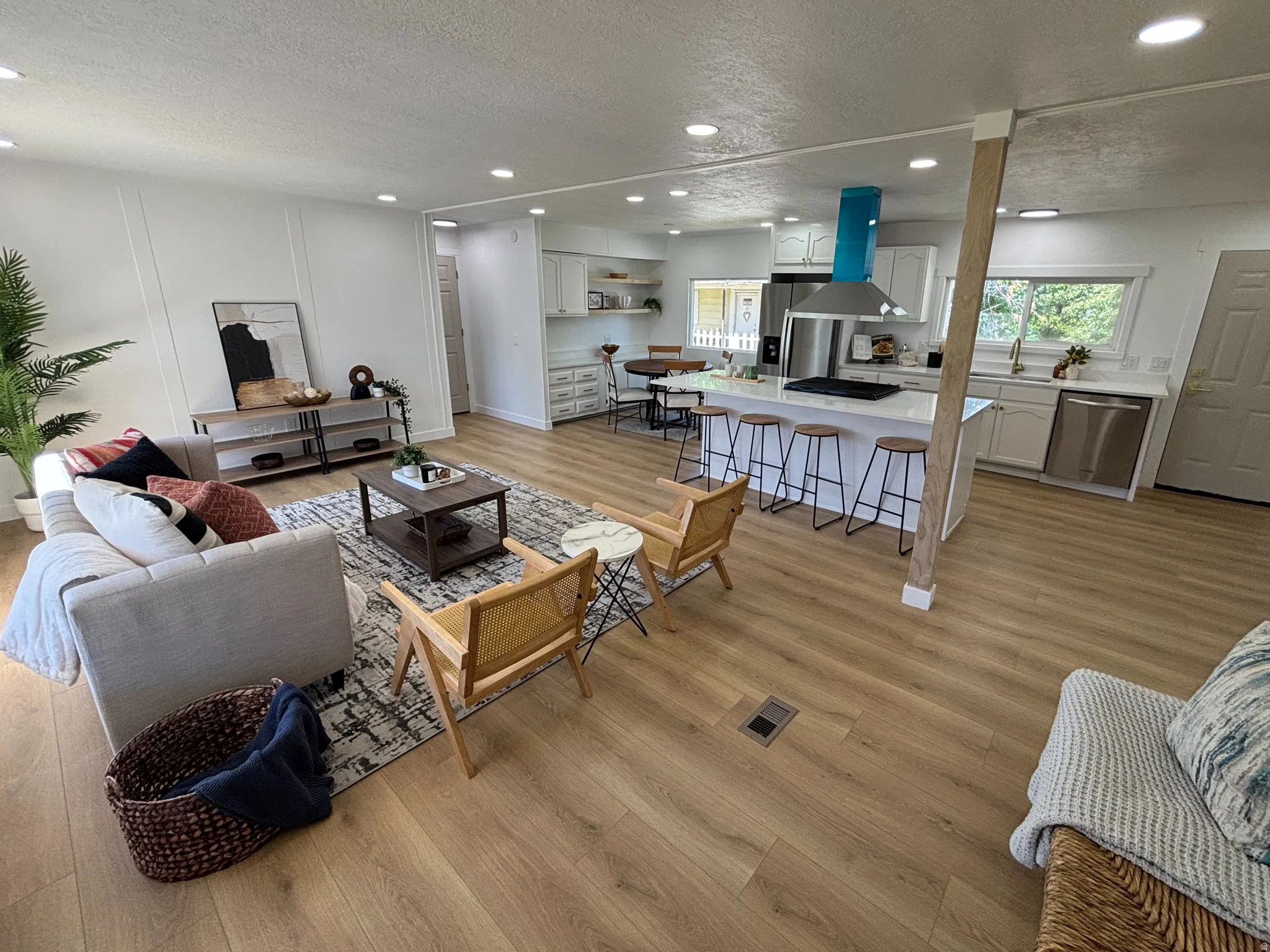 Open-concept living space featuring wood-finish flooring, recessed lighting, and a kitchen island with seating