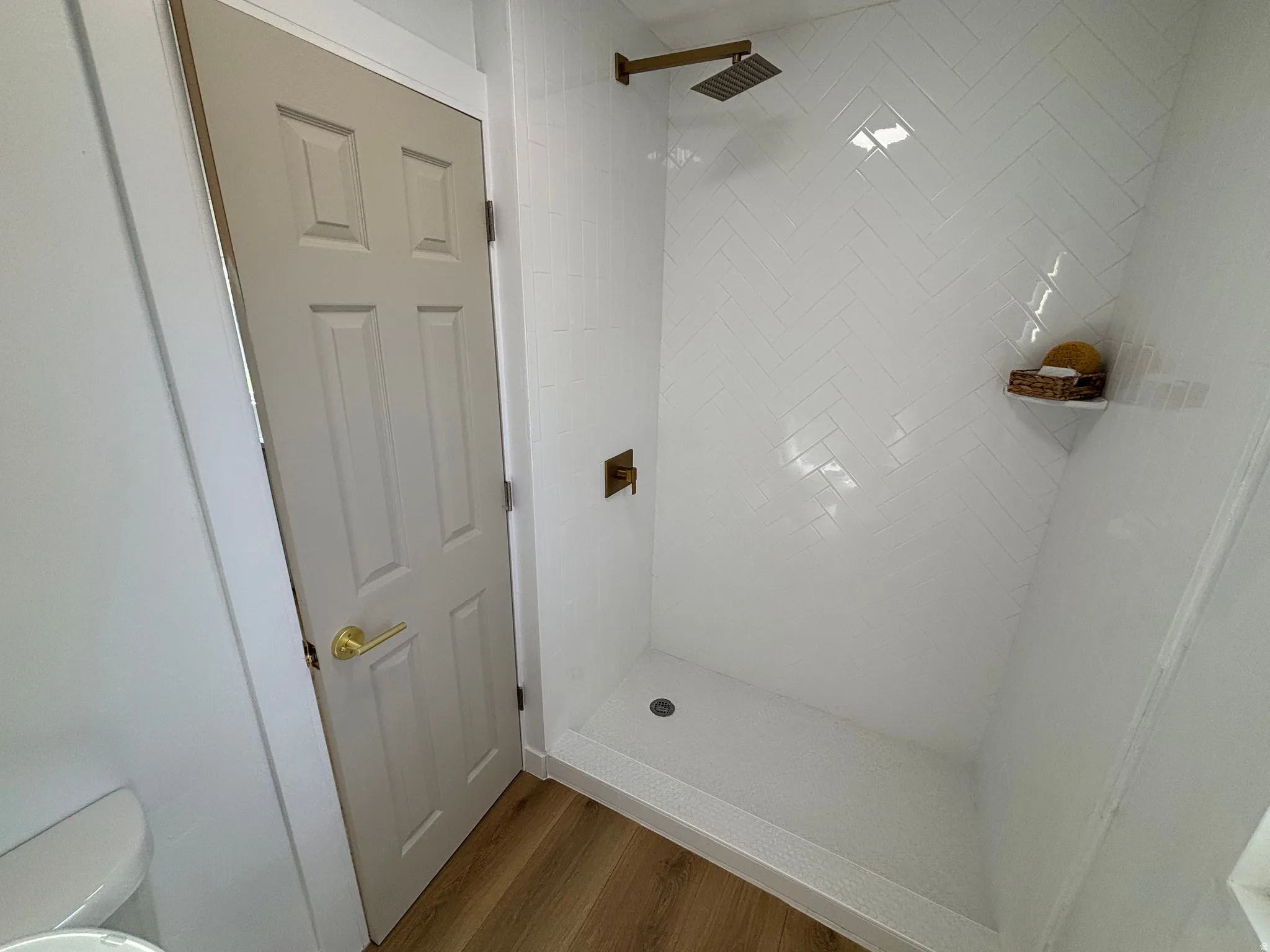 Walk-in shower featuring white subway tile in a herringbone pattern and a rain showerhead