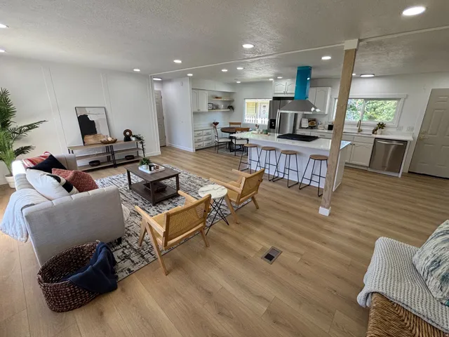 Open-concept living space featuring wood-finish flooring, recessed lighting, and a kitchen island with seating