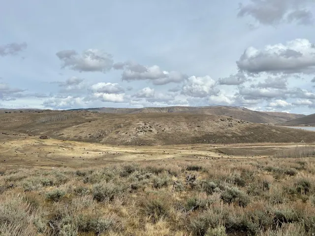 Expansive landscape with rolling hills and distant water