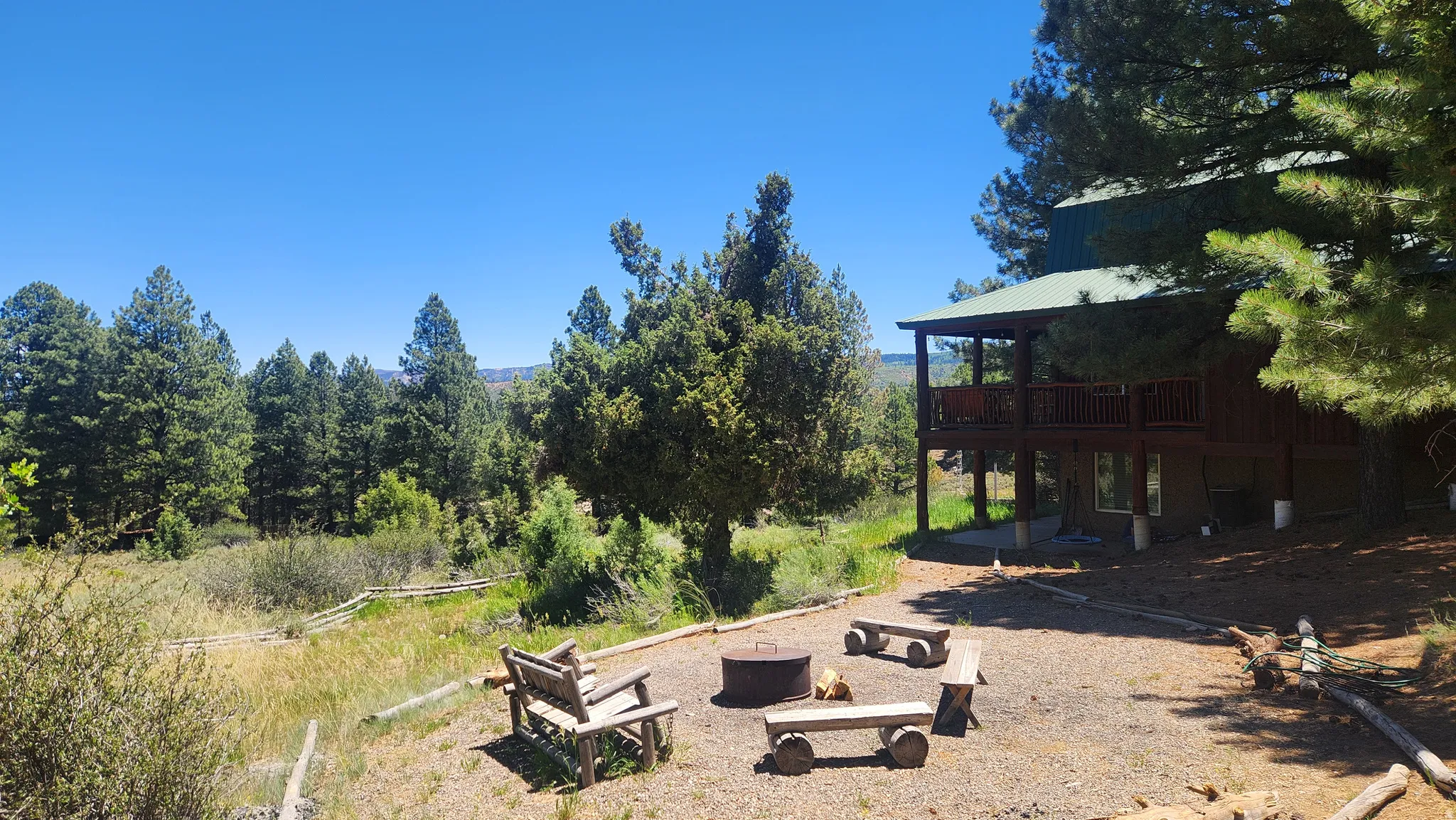 Outdoor gathering space with a fire pit, log benches, and gravel surfacing