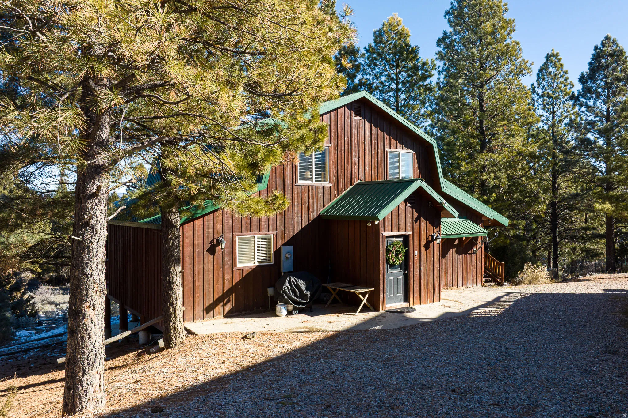 Wood-sided residence featuring a gambrel roof and green metal roofing accents
