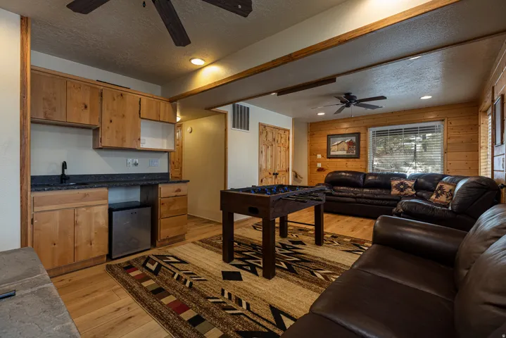 Recreational room featuring a built-in wet bar with a compact refrigerator, light wood-finish cabinetry, and dark countertop