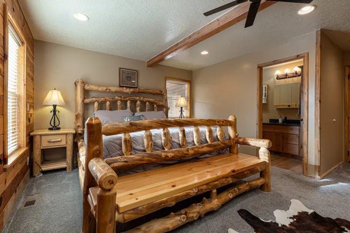 Bedroom featuring wood-paneled walls, a ceiling fan with integrated lighting, recessed lighting, and a doorway to a bathroom