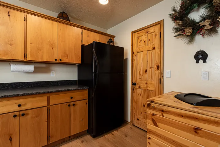 Kitchen featuring wood cabinetry with black hardware, dark speckled countertops, and wood-finish flooring