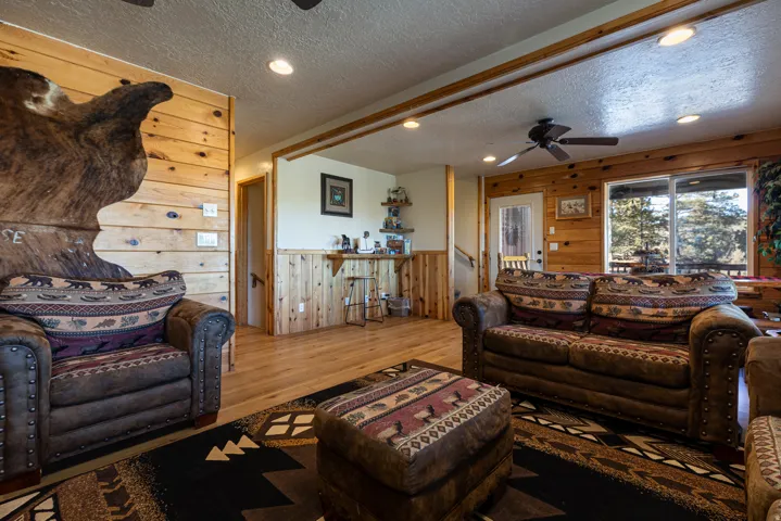Open-concept living area featuring natural wood paneling, recessed lighting, wood-finish flooring, a ceiling fan, and large sliding glass doors