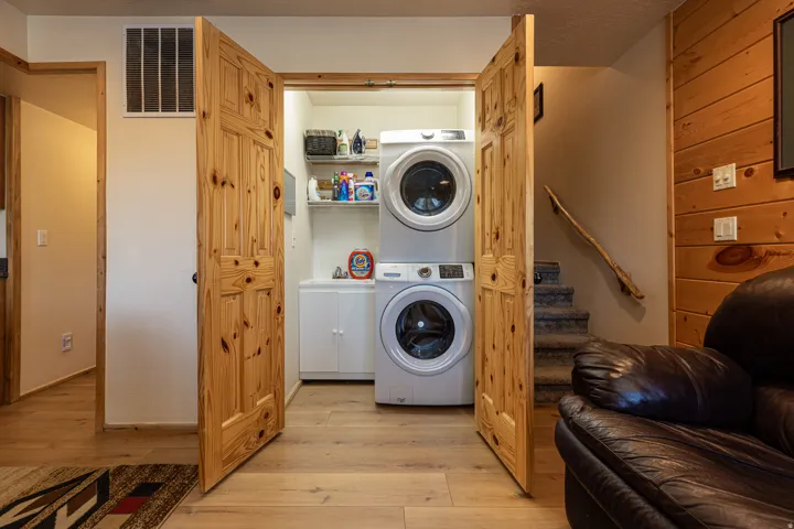Dedicated laundry closet featuring a stackable washer and dryer, built-in shelving, and a utility sink with white cabinetry
