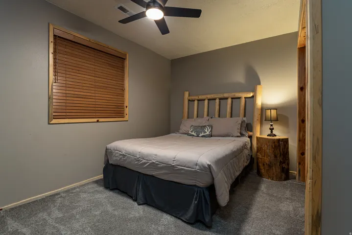 Carpeted room featuring a ceiling fan, a window with wood blinds, and natural wood trim accents