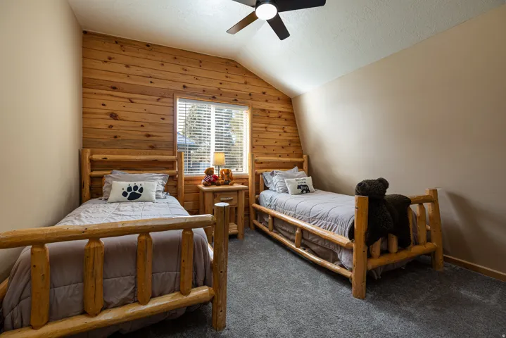 Room featuring wood plank accent wall, neutral painted walls, and textured gray carpeting