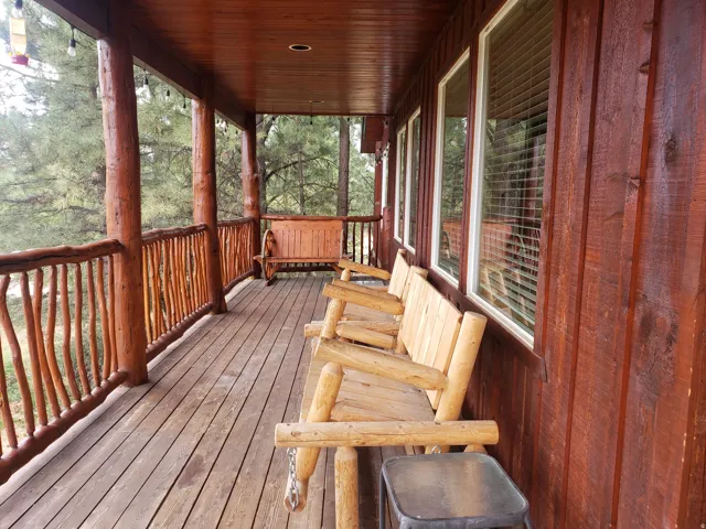 Expansive covered porch featuring wood-finish decking and rustic log railings