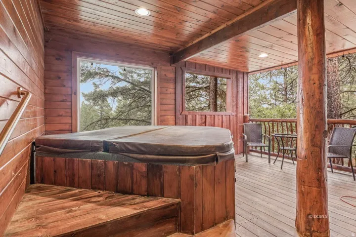 Wood-paneled room featuring a built-in spa with a cover, recessed lighting, and large windows