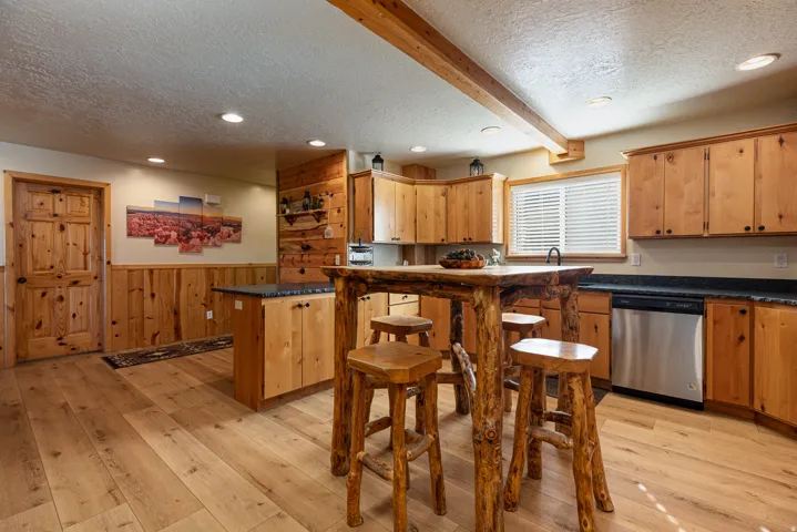 Kitchen featuring wood-finish flooring, natural wood cabinetry, and dark countertops