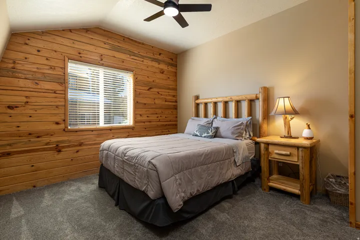 Room featuring a wood-paneled accent wall, a window with blinds, and neutral-toned walls
