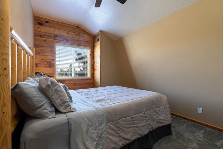 Bedroom featuring a wood-panel accent wall and a window with blinds