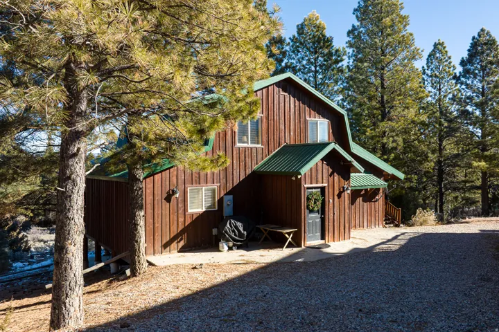 Wood-sided residence featuring a gambrel roof and green metal roofing accents
