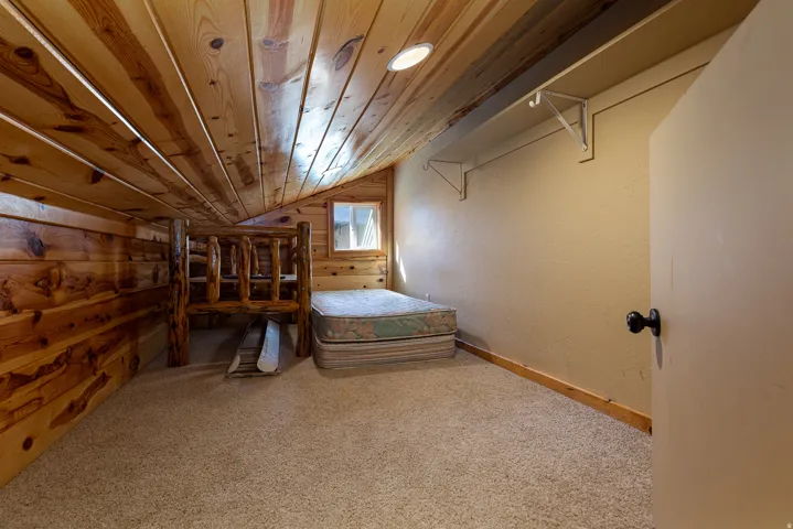 Sloped ceiling loft room featuring wood paneling, recessed lighting, and light-toned carpet flooring