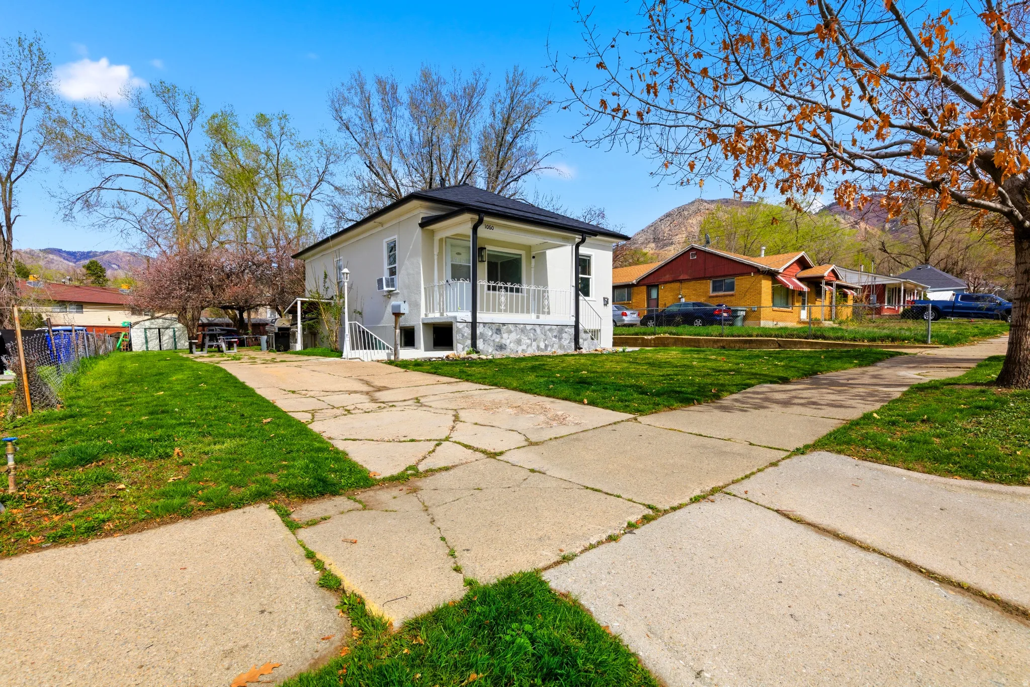 Bungalow-style home with a mountain view, concrete driveway, a porch, stucco siding, and a storage shed