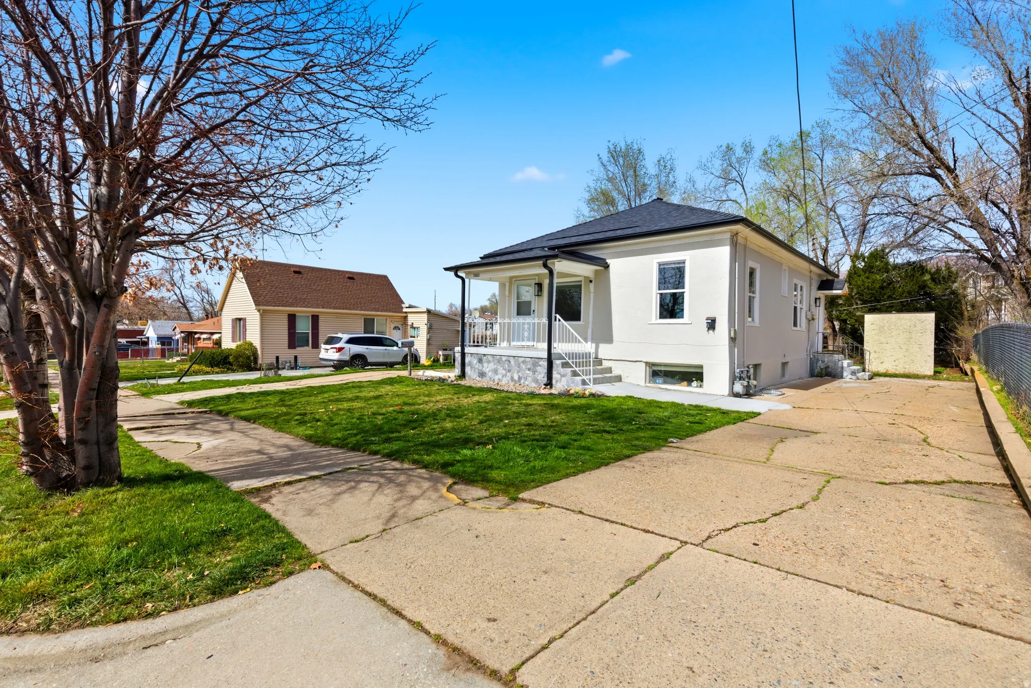 Bungalow-style home featuring a porch, a front yard, driveway, and stucco siding