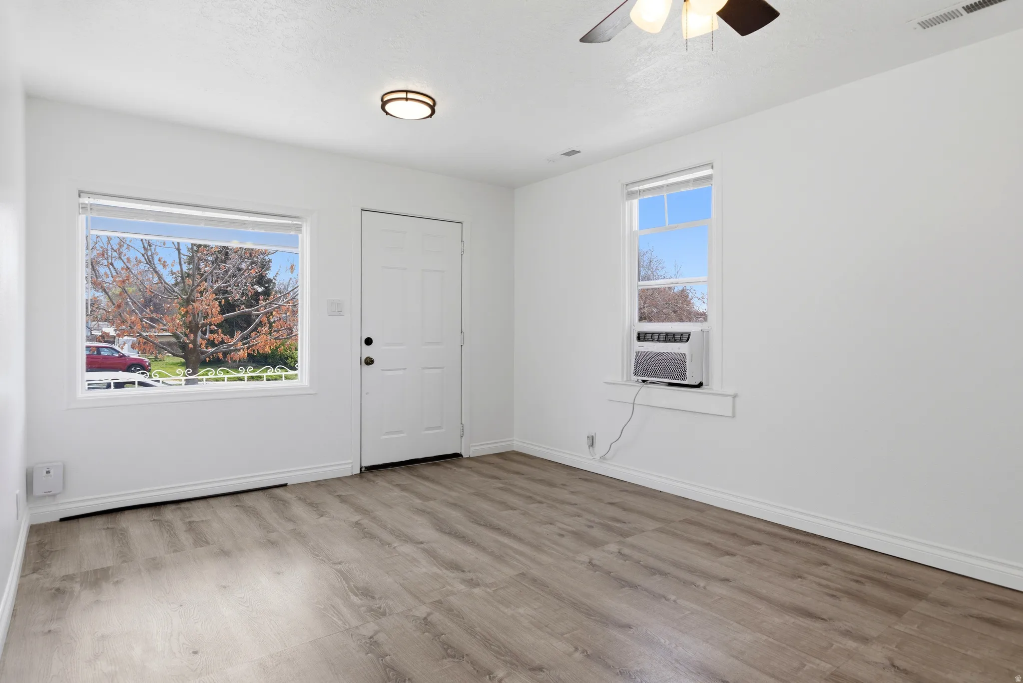 Spare room featuring light wood-style flooring, a ceiling fan, and cooling unit