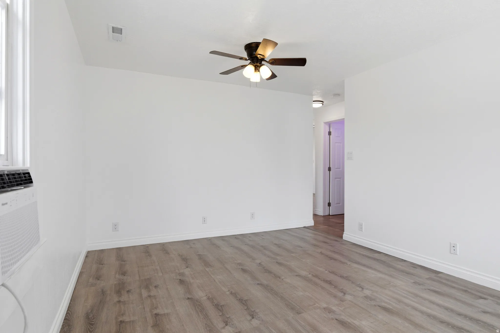 Empty room with light wood-style floors and a ceiling fan