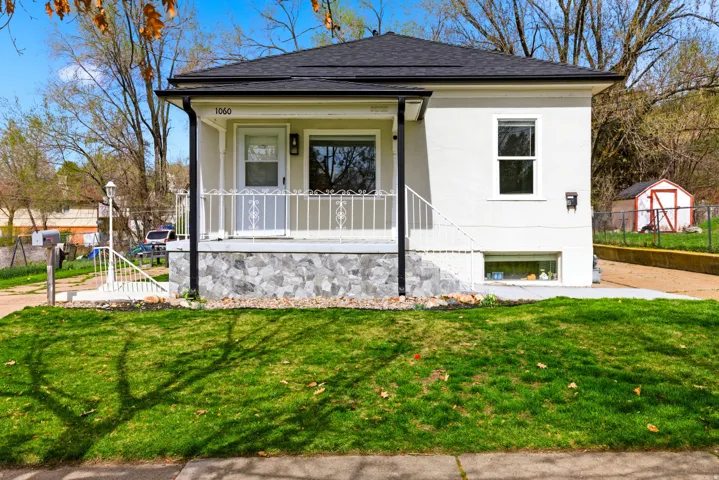 View of front facade with covered porch, a shingled roof, and stucco siding