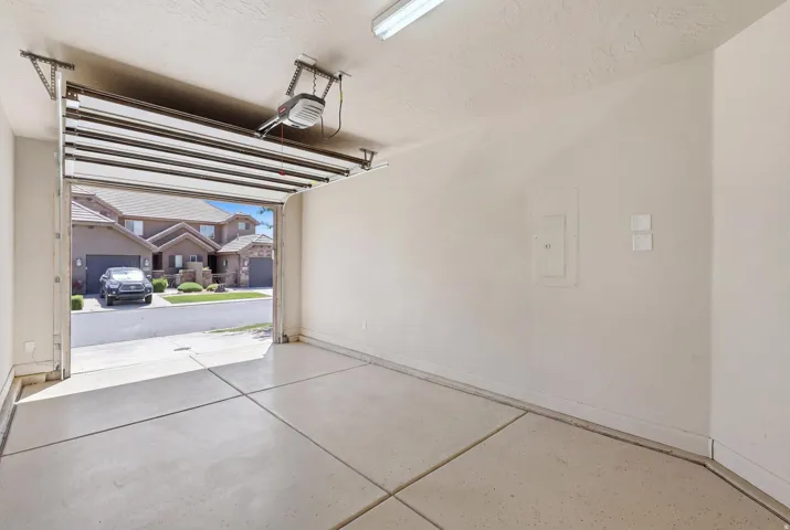 Spacious garage with light-colored concrete flooring, painted walls, and an automatic garage door opener system