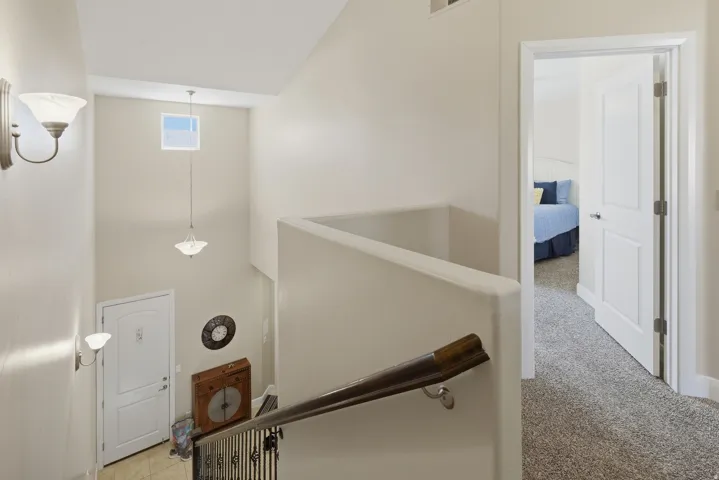 Multi-level interior featuring a staircase with a wrought iron railing, a wall-mounted sconce, and a skylight