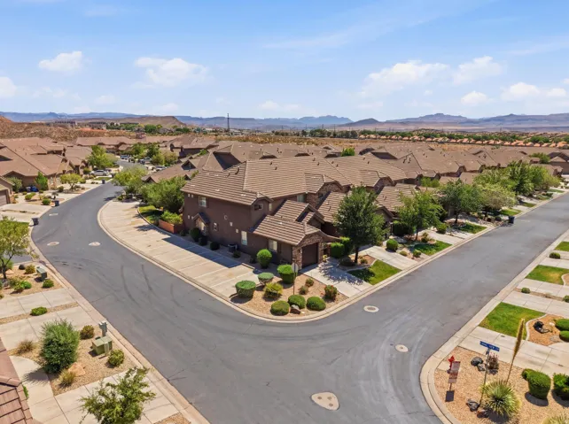Residential streetscape featuring a curved asphalt road, concrete sidewalks, and desert landscaping