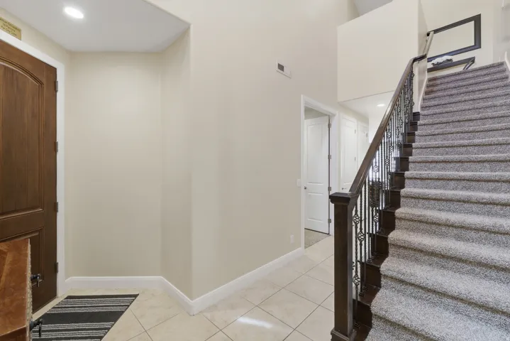 Entry foyer featuring a dark wood paneled door, light tile flooring, and white baseboards