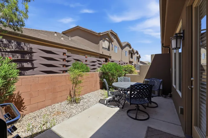 Private patio featuring a concrete slab, exterior sconce lighting, and a block wall with a decorative privacy screen