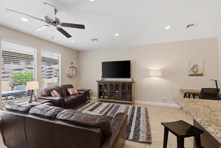 Spacious living area featuring tile flooring, multiple windows with blinds, and recessed lighting