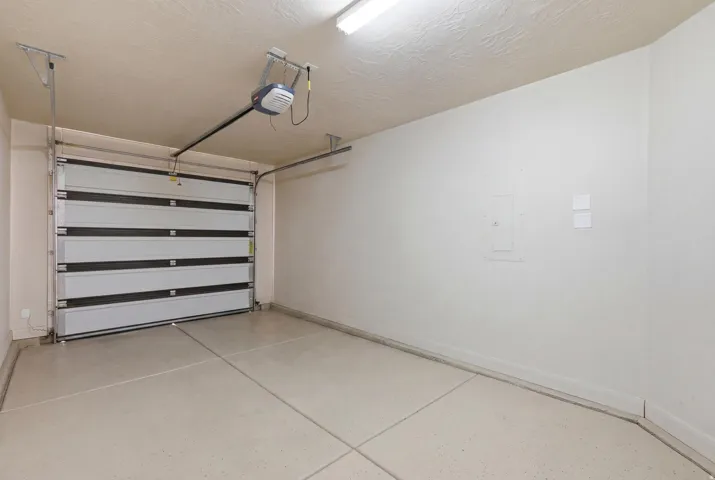 Single-car garage with an automatic overhead door and a light gray concrete floor