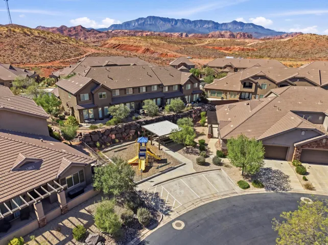 Community featuring a cul-de-sac, multiple residential units with tiled roofs, and a common area with a covered playground