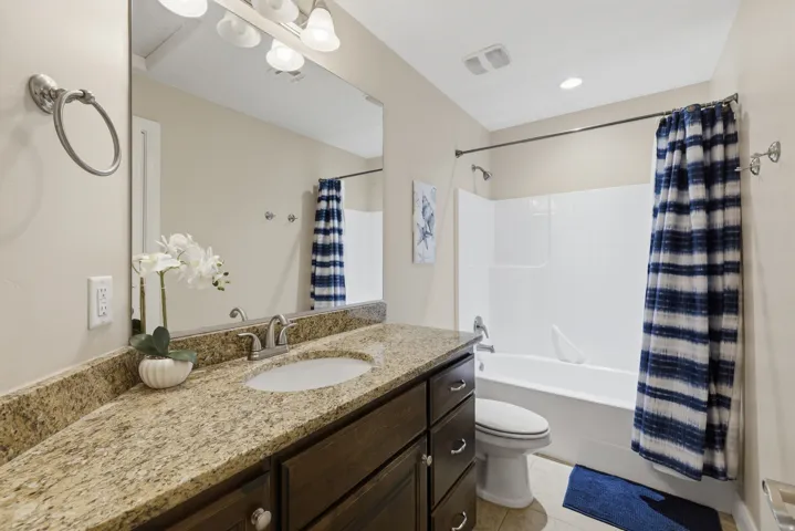 Bathroom featuring a spacious vanity with a granite countertop, undermount sink, and dark wood cabinetry