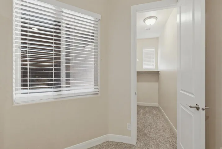 Interior room featuring light beige walls, white baseboards, and textured carpeting