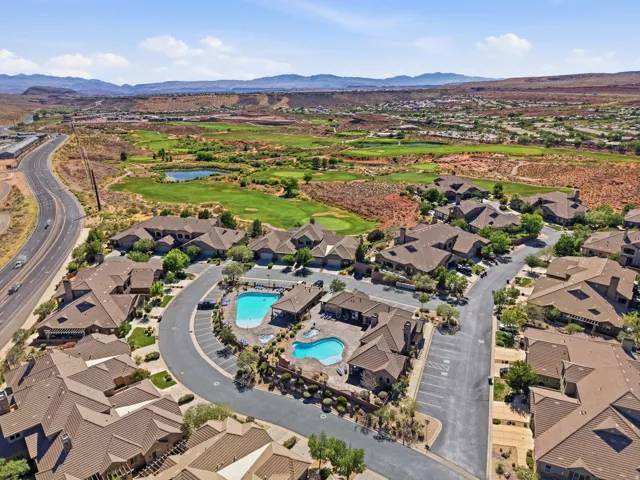 Community featuring two swimming pools, a golf course backdrop, paved roads, and extensive red rock scenery