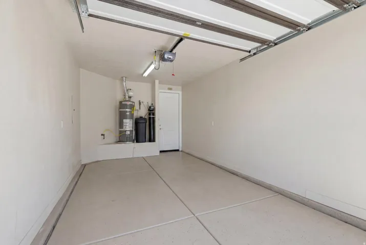 Attached garage with concrete flooring, overhead lighting, and white interior walls