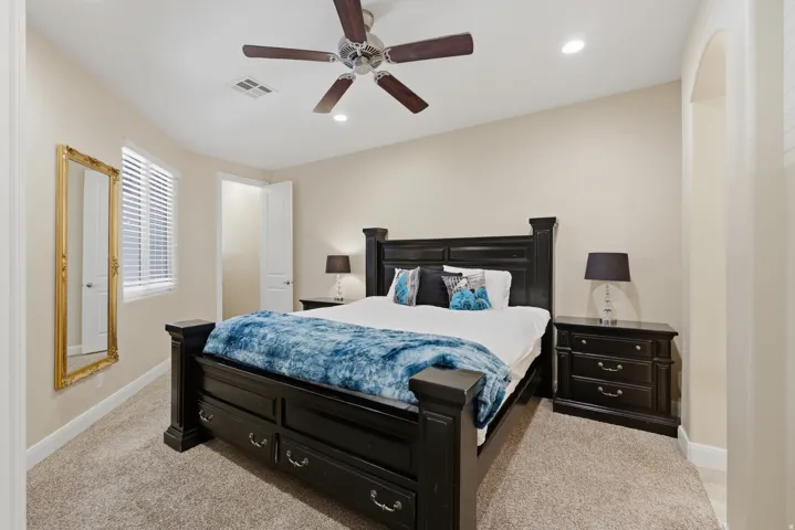 Carpeted room featuring a ceiling fan with integrated lighting, recessed ceiling lights, a window with blinds, and an arched entryway