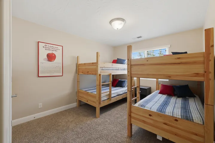 Bedroom featuring two natural wood bunk beds, neutral tone carpeting, and light beige wall paint