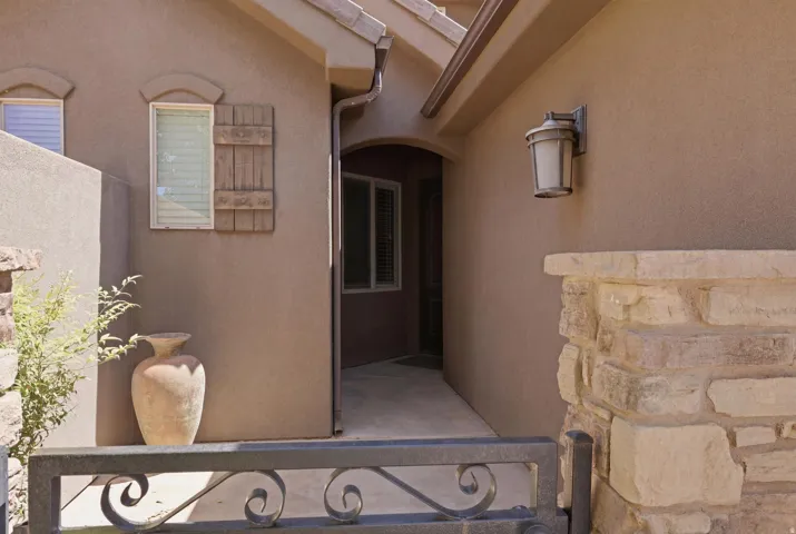 Stucco exterior with stone accents and an ornamental metal gate