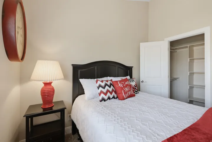 Bedroom featuring neutral wall color, dark wood-finish headboard, and integrated closet with shelving