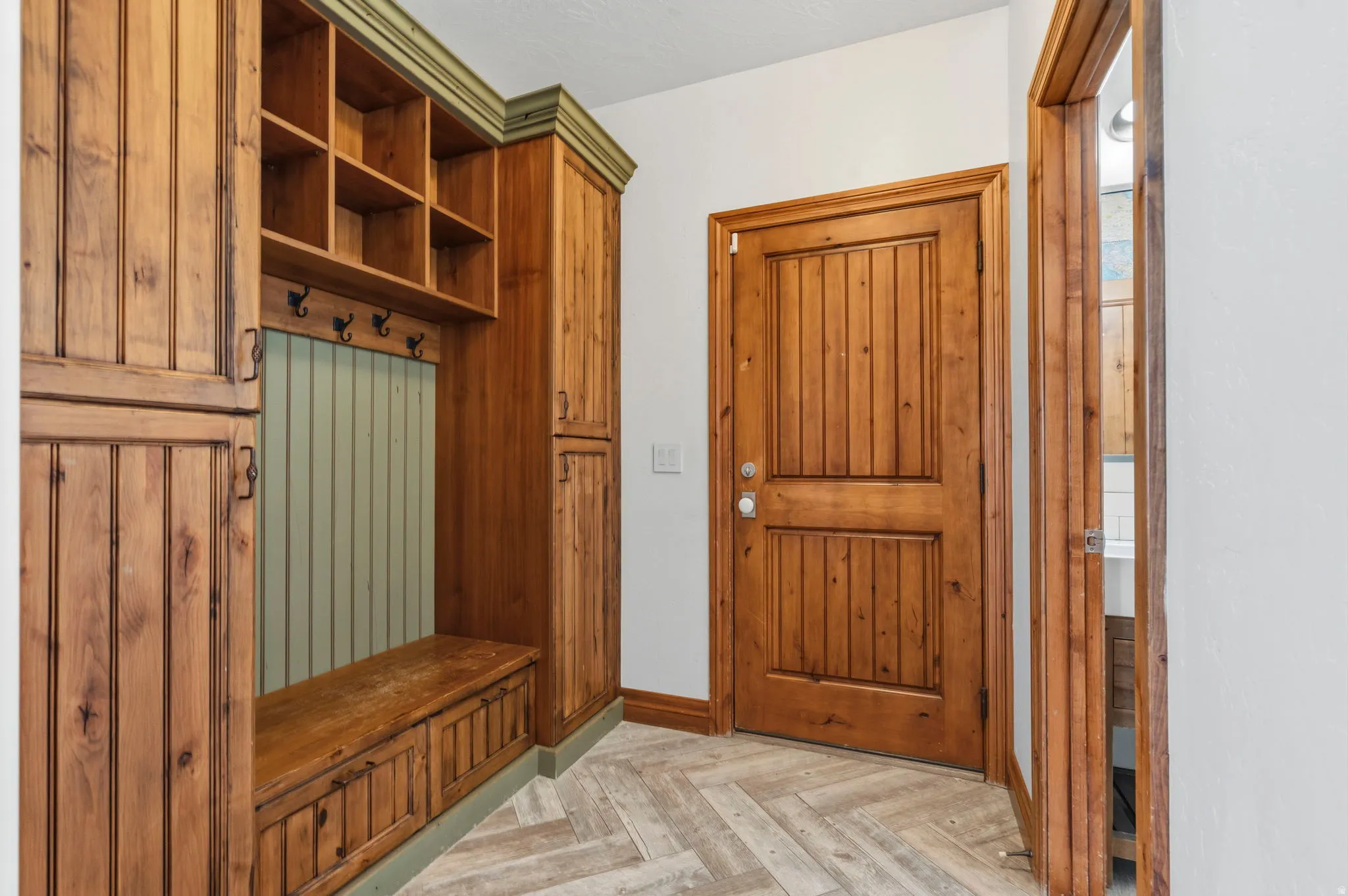 Custom built-in wood cabinetry with integrated bench seating on main level leading to garage.