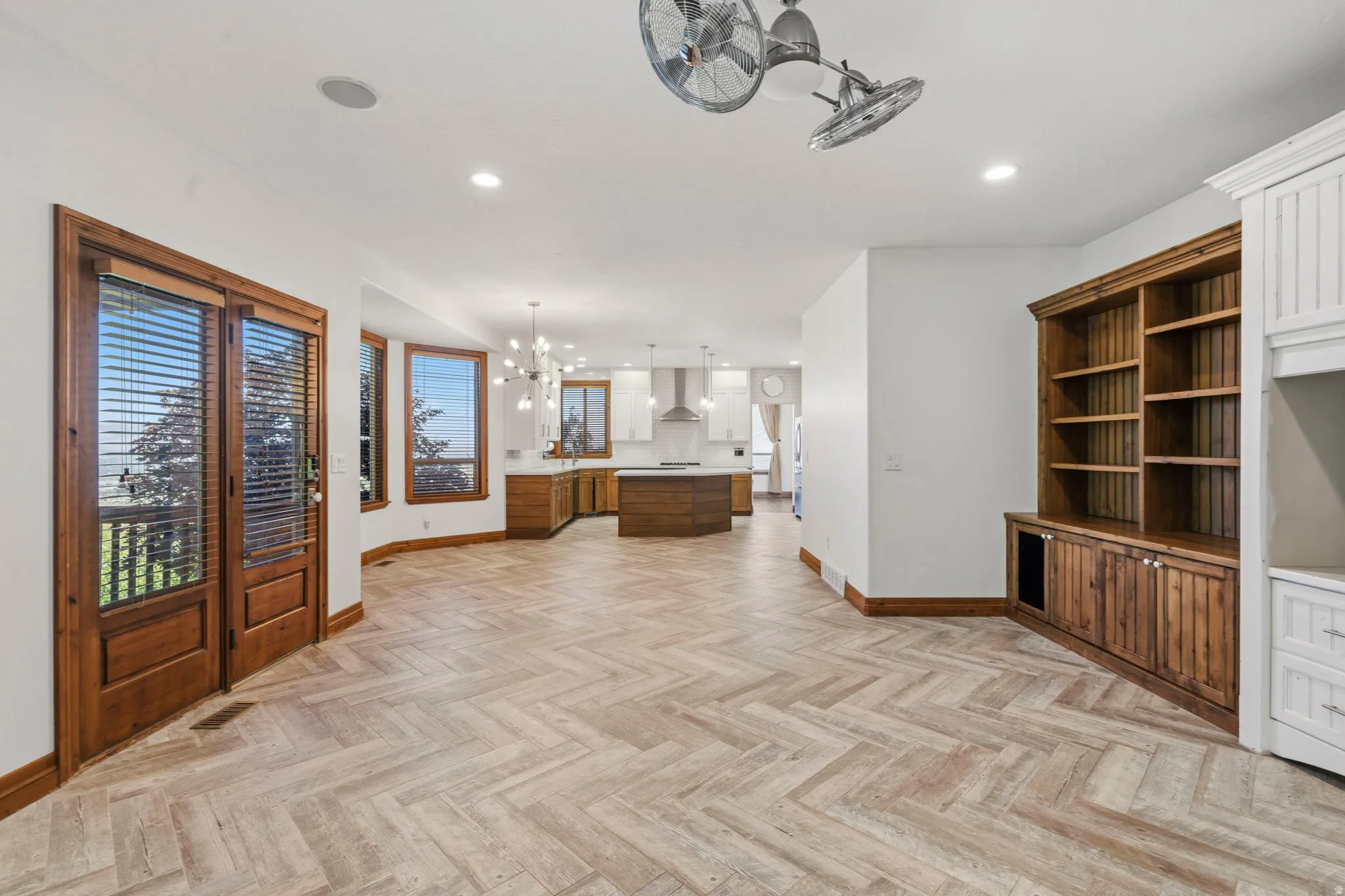 Expansive open-concept room featuring custom built-in wood shelving and glass doors to the outside deck.