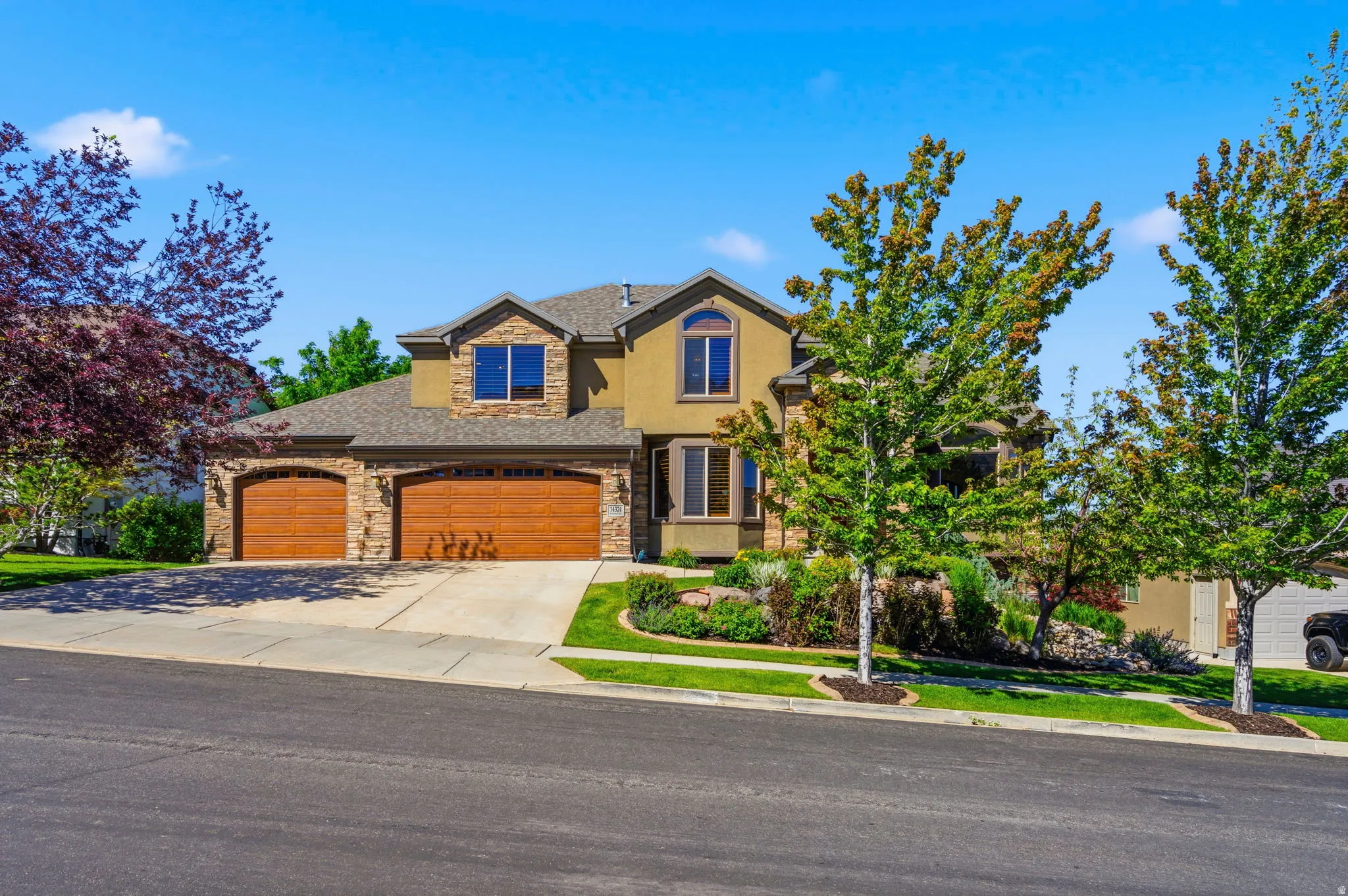 Stucco and stone facade home featuring a 3-car garage