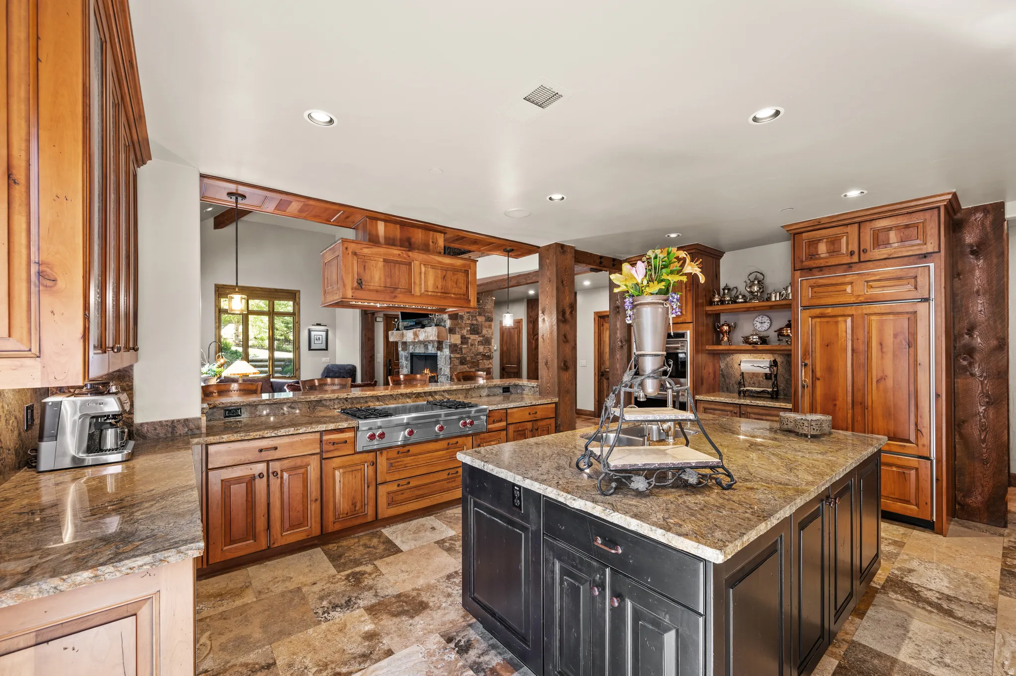 Dual tone kitchen with dark stone countertops, decorative light fixtures, open shelves, a center island, and dual tone cabinets