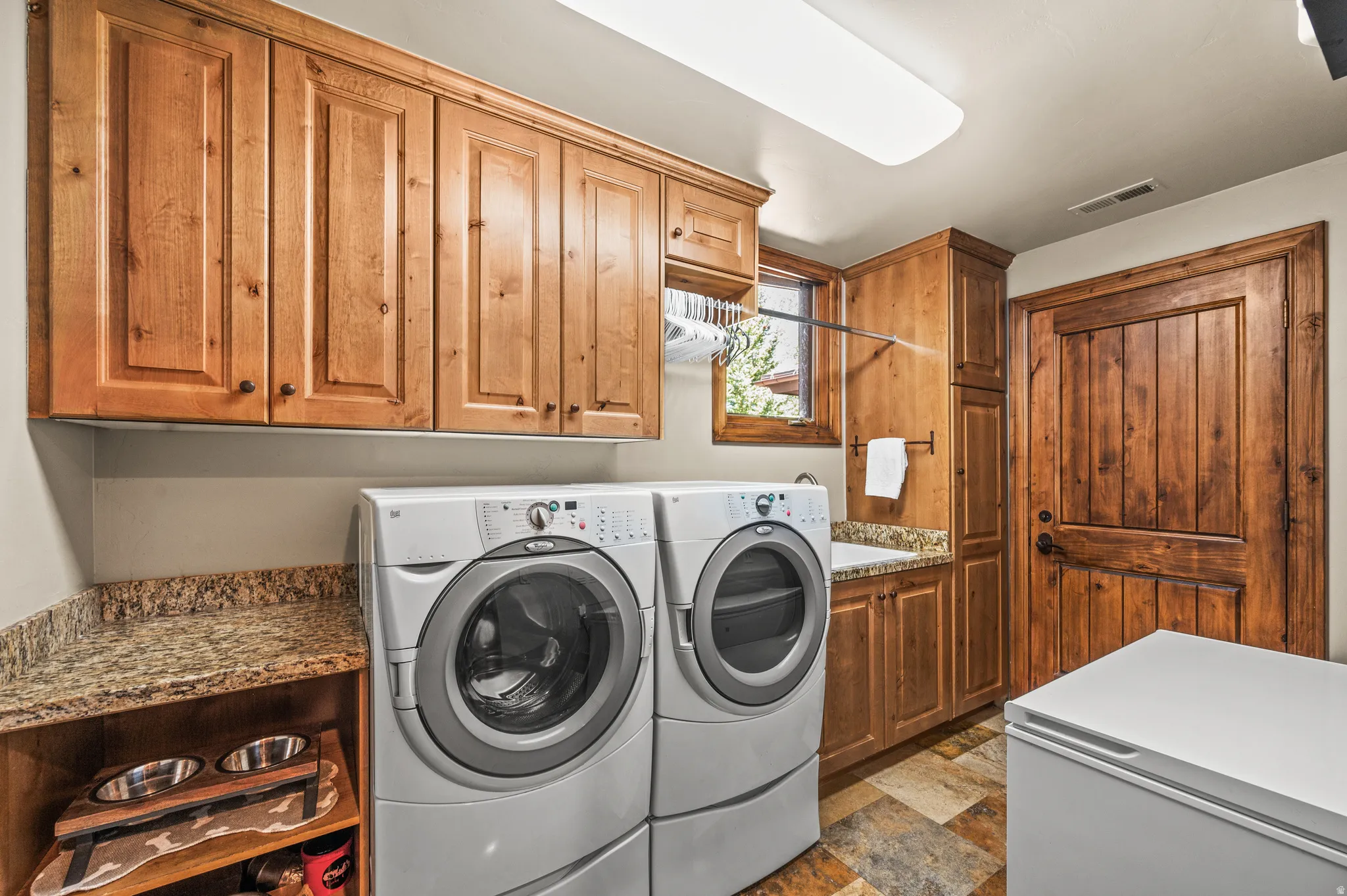 Laundry area with dark stone finish flooring, independent washer and dryer, and cabinet space